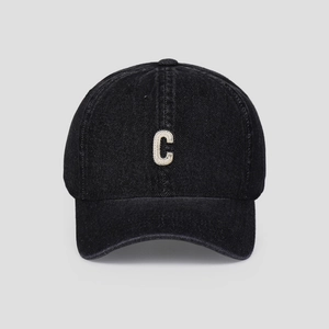 Detailed macro view of white textured letter C embroidery on black washed denim cap