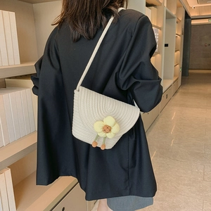 Detail of flower woven bucket bag worn by a model in a black blazer for styling