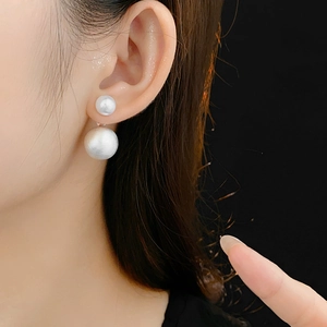 Close-up of elegant double white pearl stud earrings worn by a model in French style