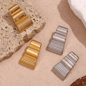 Minimalist 18K gold plated trapezoid earrings with wavy texture on a natural rock background