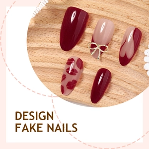 Burgundy and nude press-on nails with golden bows and red lip prints on wood pad