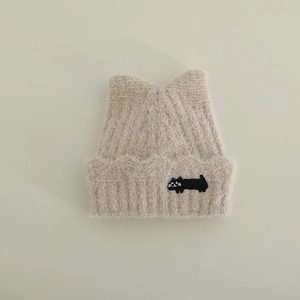 Detailed close-up of beige knit cat ear hat with cute black kitten embroidery and plush texture