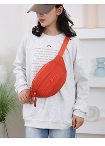 Detailed view of the orange casual crossbody chest bag with decorative woven zipper pulls