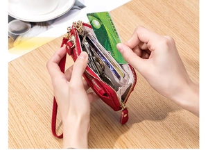 Detail of red leather wallet with double zippers holding keys, cards and coins