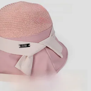 Close-up detail of a pink and beige spliced bucket sun hat featuring a woven straw crown and bow
