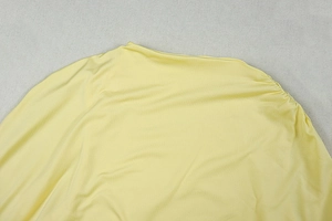 Detail of light yellow sleeveless dress showing smooth fabric and side pleated design