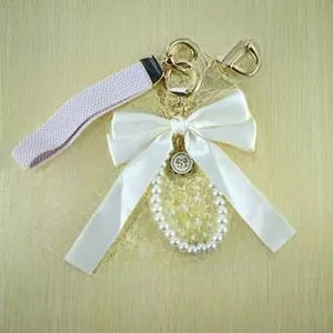 Detail of DIY pearl short chain with large white satin bow and gold metal lobster clasp
