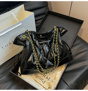 Detail of a black quilted leather chain bag with gold strap inside an elegant gift box