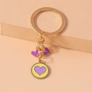 Detail of golden enamel heart charms on a keychain featuring purple and yellow patterns
