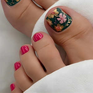 Close-up of pink and dark green press-on toenails with elegant gold floral patterns