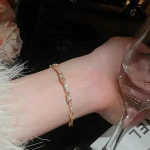 Elegant gold-plated wave bracelet with sparkling zircons worn on wrist for formal occasions