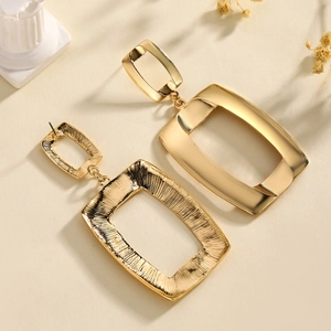 Elegant gold square geometric earrings with smooth metallic finish on neutral background