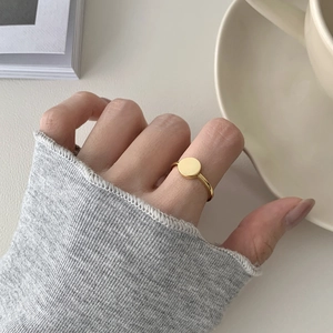 Close-up of minimalist gold circular ring on finger with elegant lifestyle background