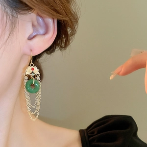 Détail de boucle d'oreille Pipa avec pierre de jade verte et franges dorées élégantes