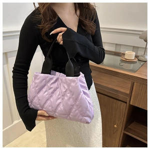 Detail of lavender quilted puffer handbag with black webbing handles for casual wear