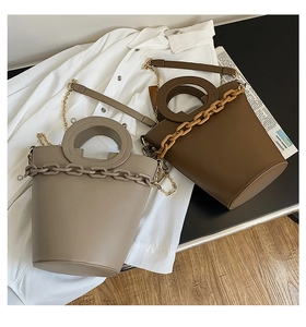 Detail of light gray and dark brown bucket bags with round handles and thick chain decor