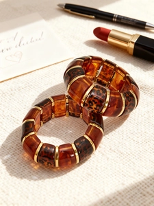 Detail of leopard print resin bracelets with gold metal accents on creamy fabric