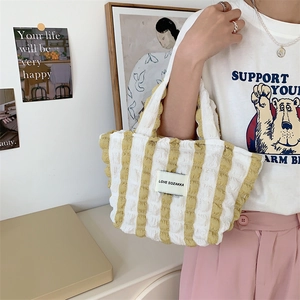 Detail of yellow striped bubble tote bag with textured seersucker fabric and brand label