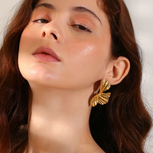 Close-up of golden ginkgo leaf earrings with embossed texture on a model side profile