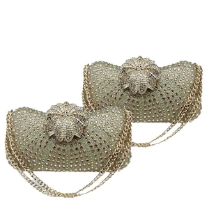 Luxurious champagne gold evening bag with rhinestones and a floral clasp on white background