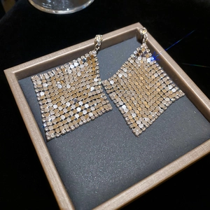 Detail of silver diamond-studded geometric dangle earrings in a luxury jewelry box