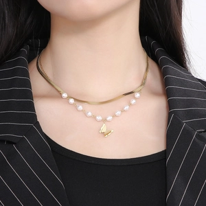 Detail of layered gold snake chain with white pearls and frosted butterfly pendant