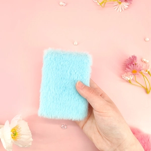 Primo piano di un mini taccuino in peluche celeste con trama morbida e sfondo floreale