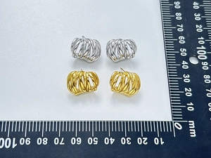 Detail view of gold and silver C-shaped multi-layered earring studs with measurement scale