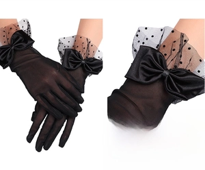 Detail of black mesh bridal gloves featuring satin bows and polka dot ruffled cuffs