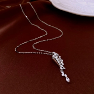 Detail of silver drop zircon necklace with tassel pendant on dark silk background