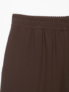 Detail of dark brown crepe fabric showing elastic waistband and premium stitching quality