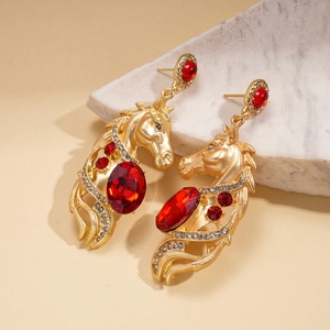 Detail of vintage horse head earrings with red rhinestones on a beige textured base