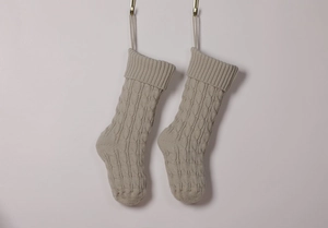 Detail of two beige knitted Christmas stockings with classic cable stitch patterns