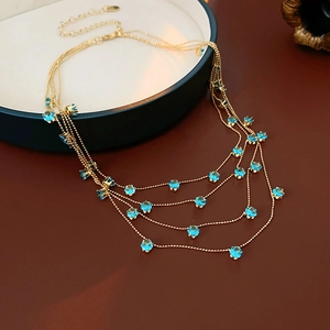 Détail d'un collier doré multicouche avec zircons bleus sur un plateau à bijoux