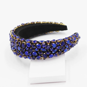 Gros plan de strass bleu roi sur un serre-tête large en velours noir et métal doré