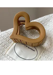 Detailed close-up of a matte caramel heart-shaped claw clip on white textured fabric