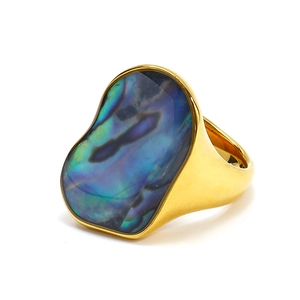 Detailed macro view of an irregular abalone shell inlay on a thick 18K gold band ring