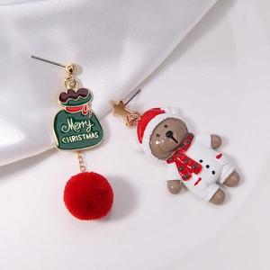 Detailed shot of asymmetric Christmas earrings with red pom-poms and a festive bear