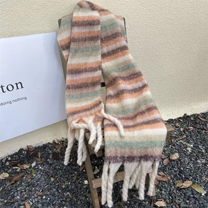 Detail of colorful plaid scarf with soft fringe tassels hanging on a wooden chair