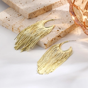 Detail of elegant gold tassel earrings with tiered metal chains on stone display
