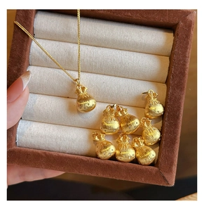 Makroaufnahme von Gold-Glücksbeutel-Anhänger mit Zirkonia-Steinen und gebürsteter Oberfläche