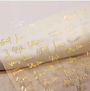 Macro shot of gold embossed nail stickers with stylish cursive metallic lettering textures