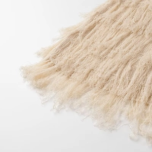 Détail macro du tissu en maille beige avec franges texturées et motifs tissés