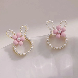 Detailed view of silver rabbit stud earrings with white pearls and a pink floral accent