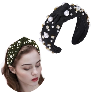 Detail of velvet knotted headband with pearls and rhinestones on emerald and black fabric