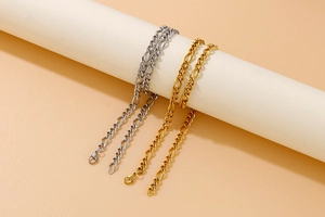 Detail of gold and silver Figaro link chains hanging on white cylindrical props