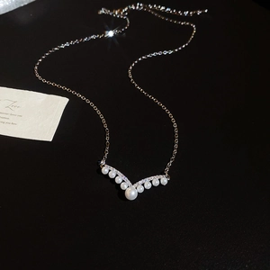 Macro shot of V-shaped pearl necklace with sparkling zircon on a delicate gold chain