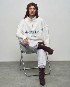 Close-up of white oversize sweatshirt featuring a half-zip neckline and letter print details