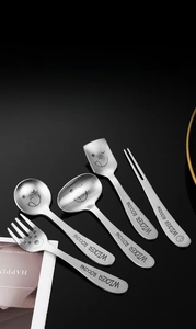 Close-up of 5-piece stainless steel dessert spoon set with smiling face engravings