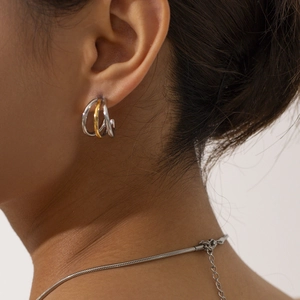 Modern two-tone gold and silver stainless steel triple layer hoop earrings on a model